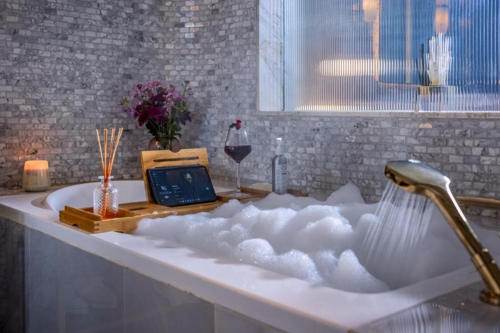 a bathtub filled with snow with a laptop and a glass of wine at Glee Nairobi, a Preferred LVX Hotel in Nairobi