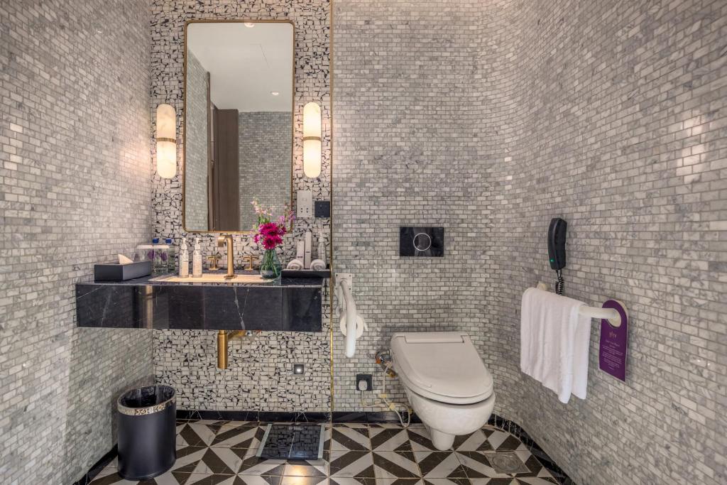 a bathroom with a toilet and a sink and a mirror at Glee Nairobi, a Preferred LVX Hotel in Nairobi