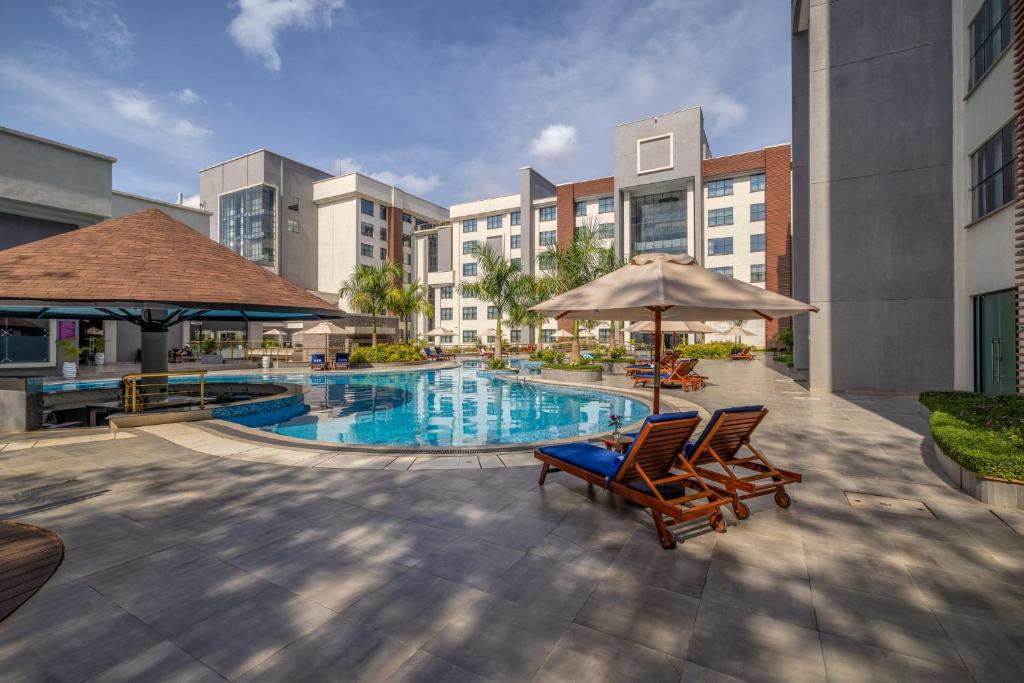 a swimming pool with chairs and umbrellas in a building at Glee Nairobi, a Preferred LVX Hotel in Nairobi