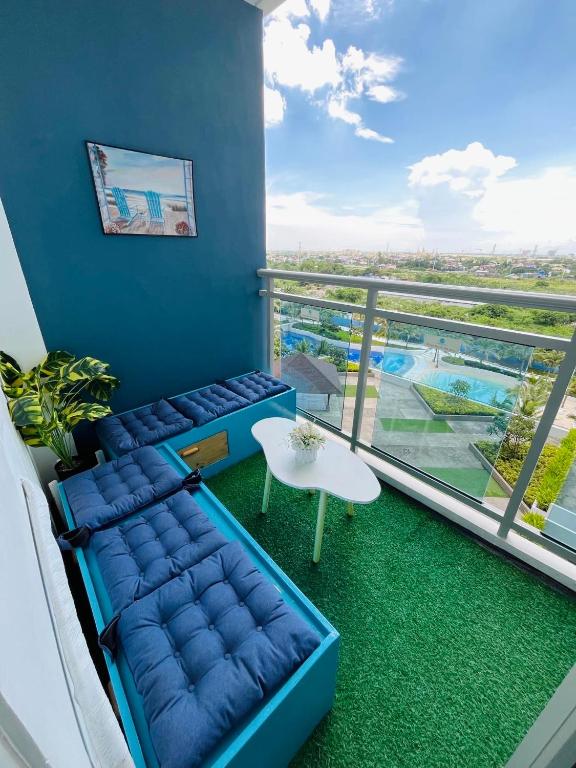 a living room with a blue couch and a balcony at Beach Vibe Condo with PS4, Mini Karaoke, Board Games in Azure North San Fernando Pampanga in San Fernando