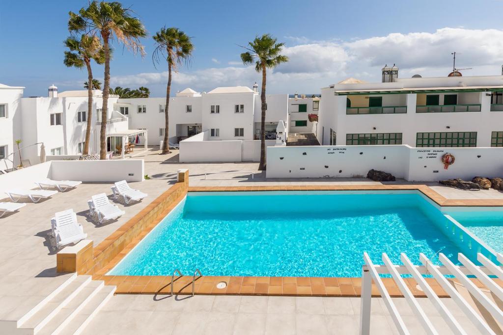Una piscina con sillas frente a un edificio. en Lanzahost Tabaiba Blue, en Costa Teguise