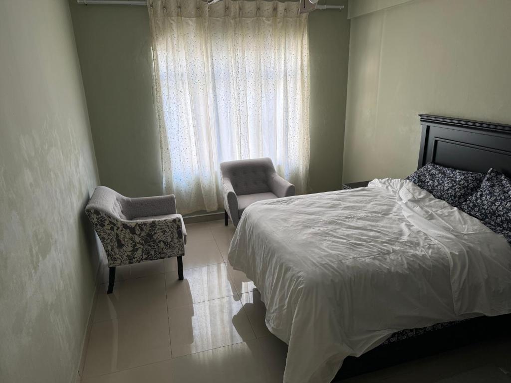 ein Schlafzimmer mit einem Bett und zwei Stühlen und einem Fenster in der Unterkunft Feel At Home Away From Home in Durban