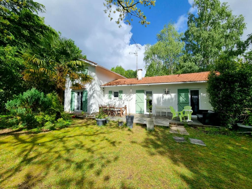 une petite maison blanche avec une cour et une maison dans l'établissement La Cabane aux Acacias~vacances nature et au calme, à Mézos