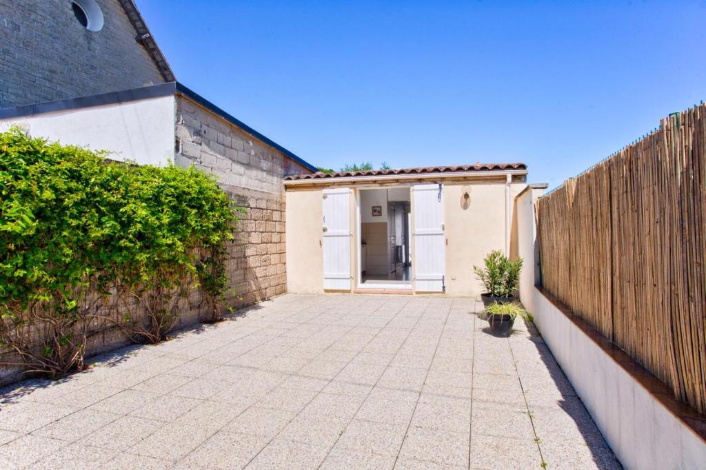 a driveway with a white door and a wooden fence at L'atypique, avec terrasse à 150M de la plage in Lion-sur-Mer