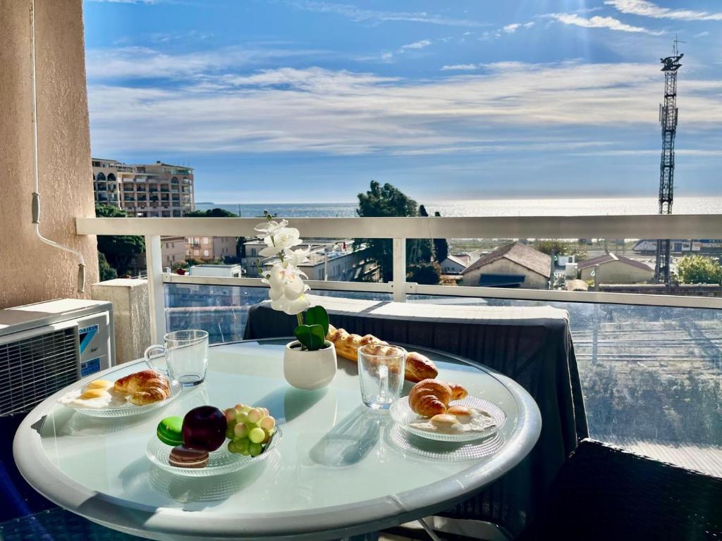 une table avec des assiettes de nourriture sur un balcon dans l'établissement L'Eburneen YourHostHelper, à Cannes