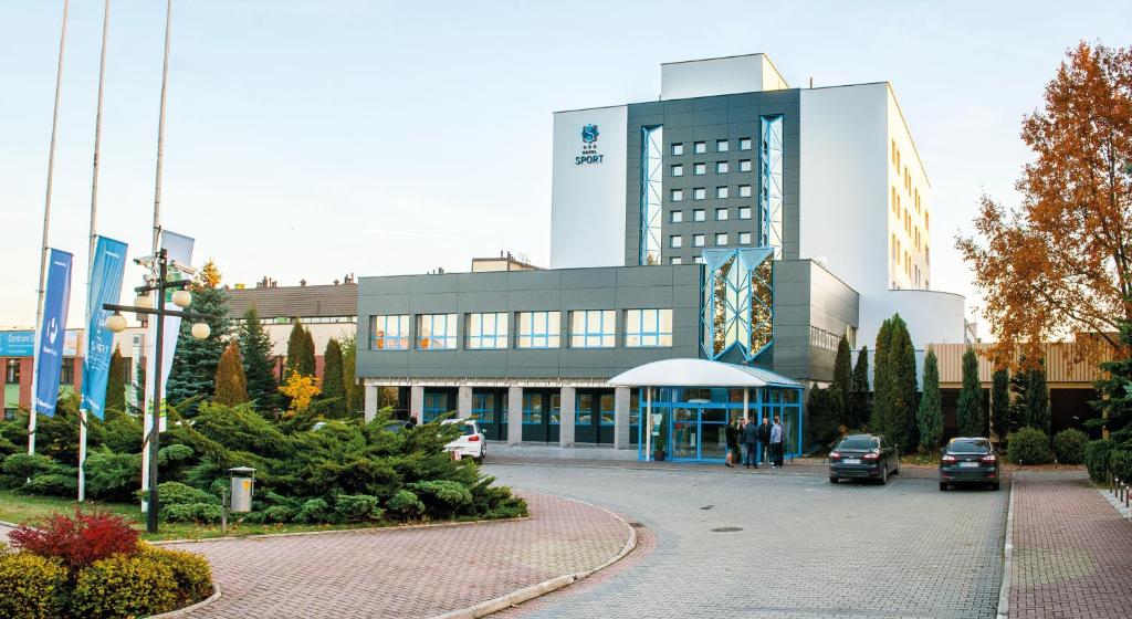 a large building with cars parked in front of it at Hotel Sport in Bełchatów