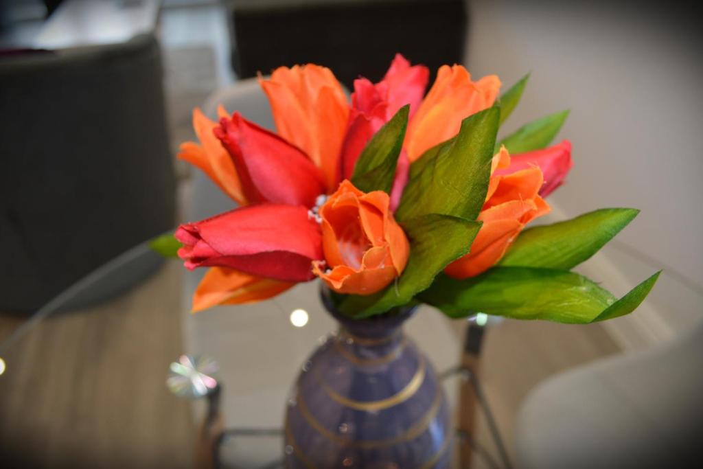 a blue vase with orange and red flowers in it at Hatfield Gem - 1 Bed with FREE Parking near Uni, Business Park & City Center, Big savings on Longer Stays in Hatfield