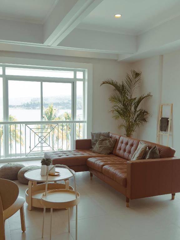 a living room with a brown couch and a table at Beachside Sunset Oasis at Canyon Cove in Nasugbu