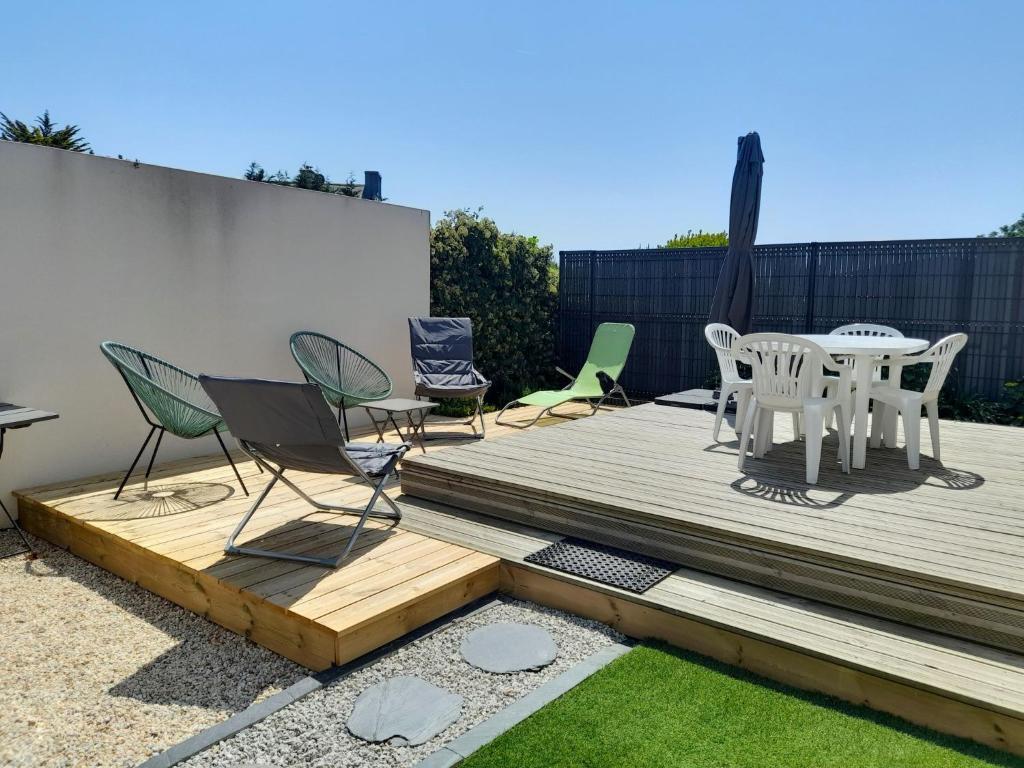 une terrasse en bois avec des chaises et une table. dans l'établissement Maison 2 pièces 4 personnes proche de l'océan - GAELIG, à Sarzeau