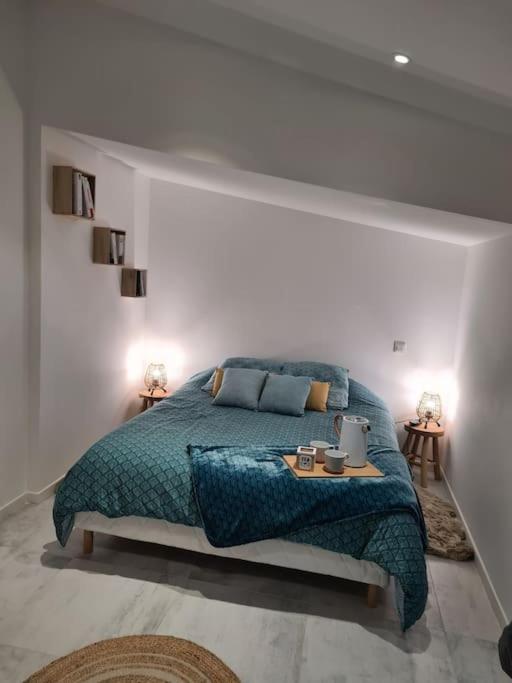 - une chambre blanche avec un lit et une couverture bleue dans l'établissement Hébergement, à Ouistreham
