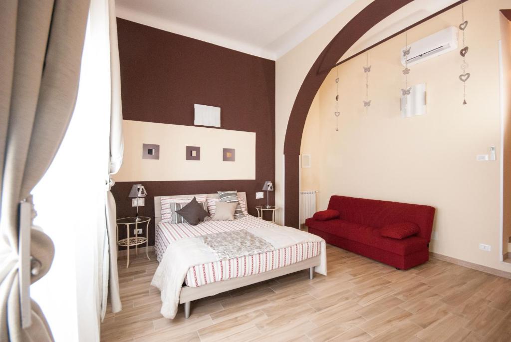 1 dormitorio con 1 cama y 1 sofá rojo en Le Mie Stelle, en La Spezia