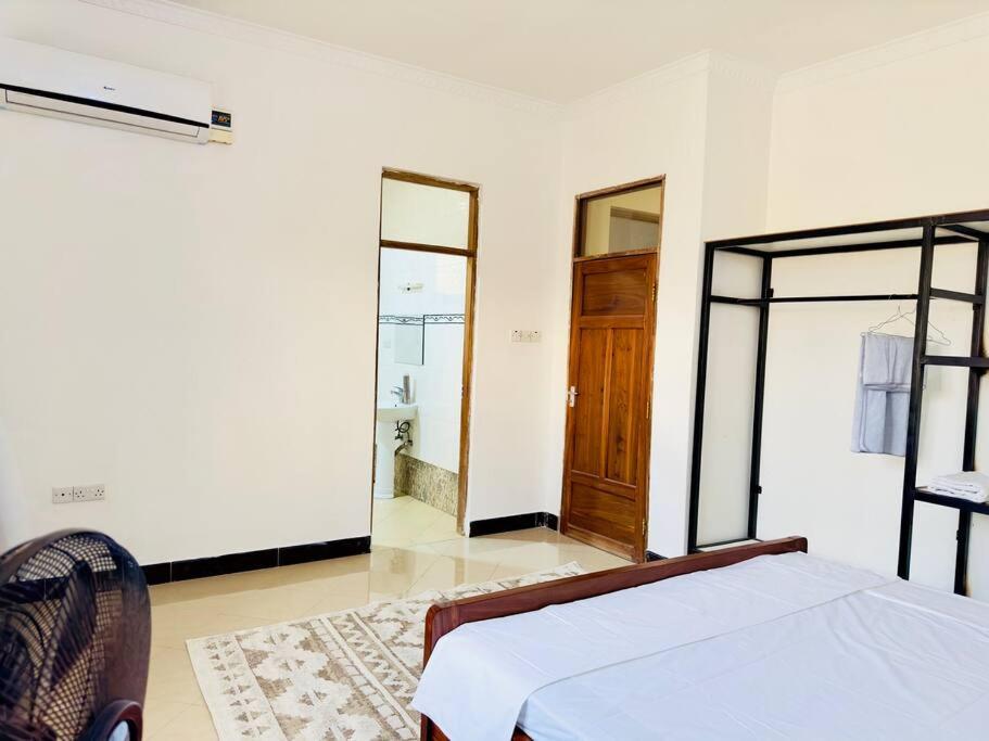 Habitación blanca con cama y baño. en Sallys cozy home, en Dar es Salaam