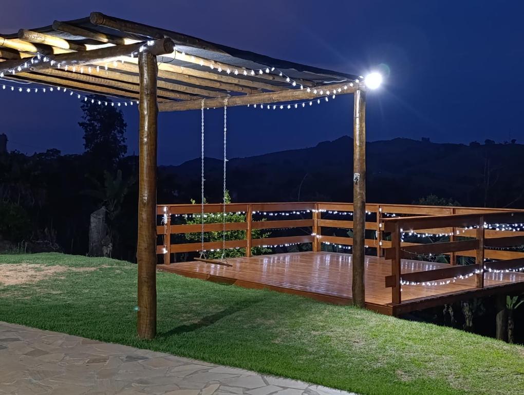 une pergola en bois avec des lumières sur une terrasse la nuit dans l'établissement Chácara Santa Luzia, à Socorro