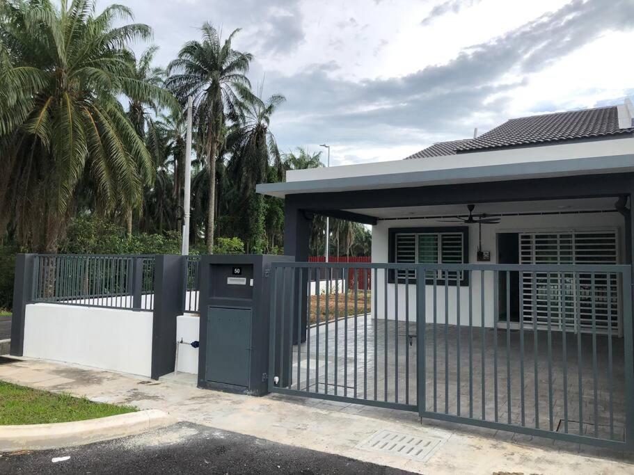 a gate in front of a house with palm trees at SK Villa's Homestay Kota Warisan, Dengkil, KLIA in Sepang