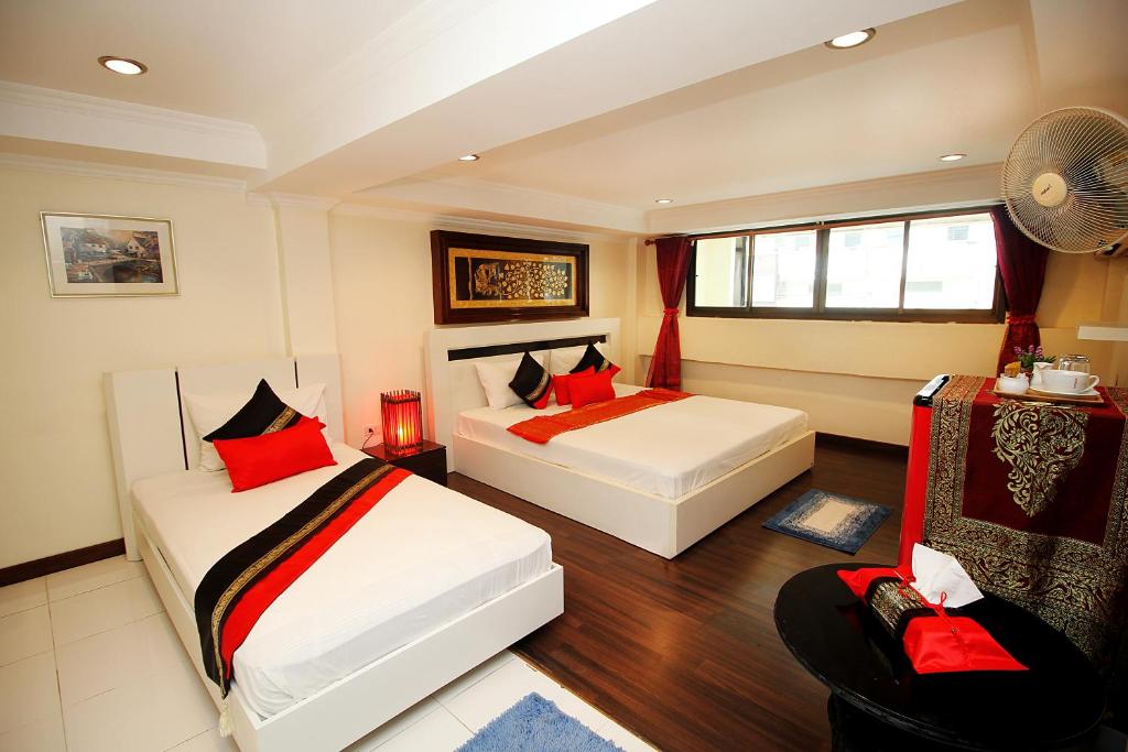 a bedroom with two beds and a fan at Sky Silk Decoration House in Patong Beach