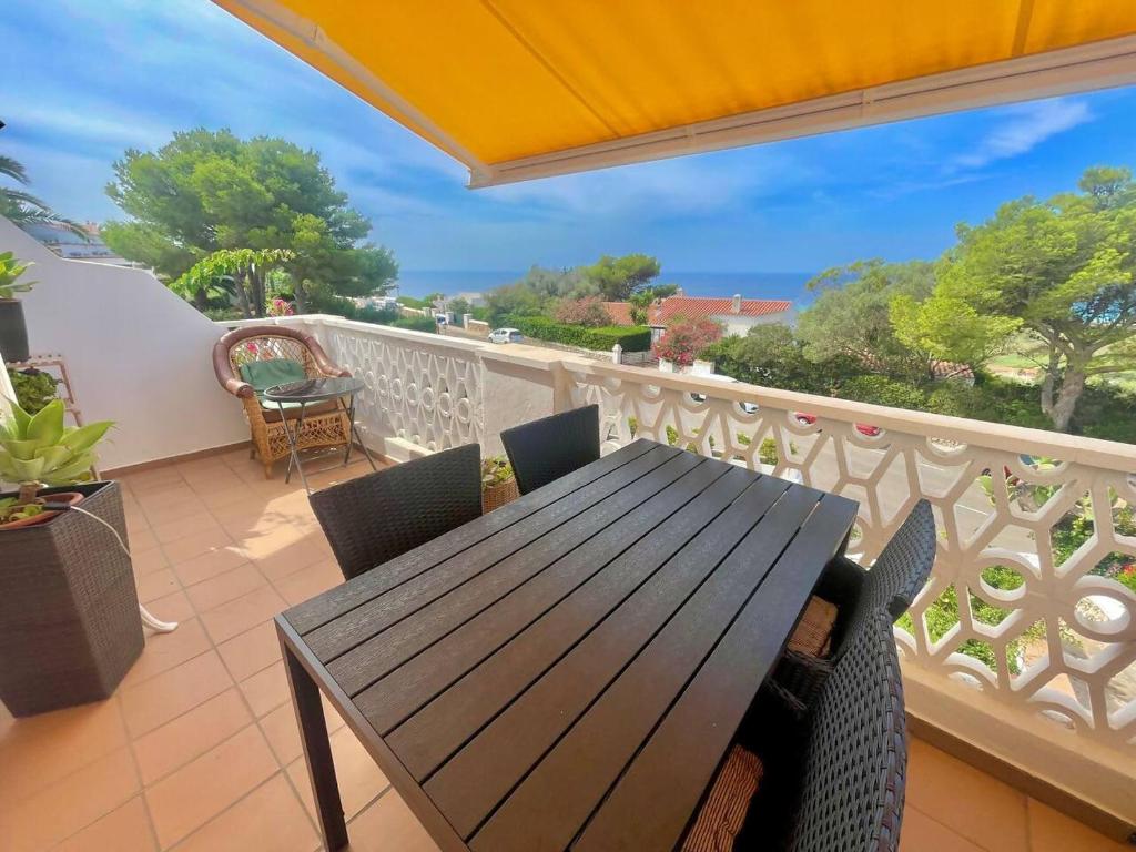 een terras met een houten tafel en stoelen op een balkon bij Suite with views of son bou beach in Son Bou