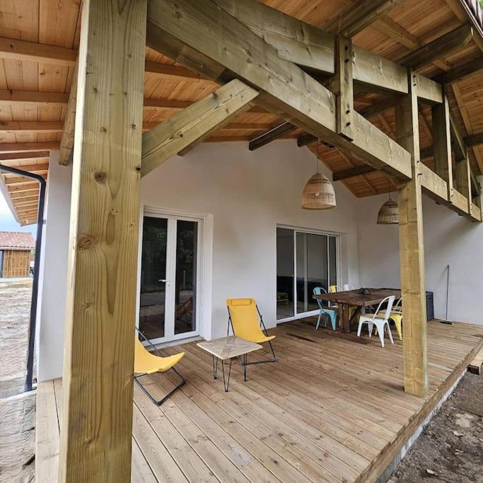 une grande terrasse en bois avec des chaises et une table dans l'établissement La Litoise, à Lit-et-Mixe