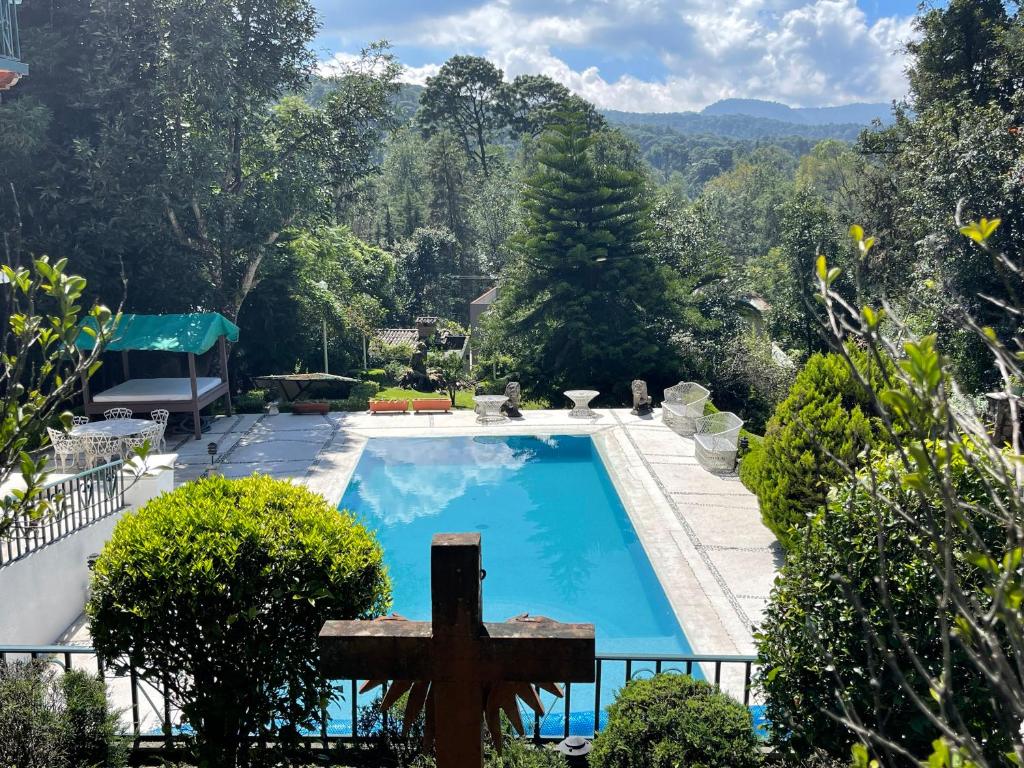 a view of a swimming pool in a garden with a cross at Villa San Francisco in Valle de Bravo