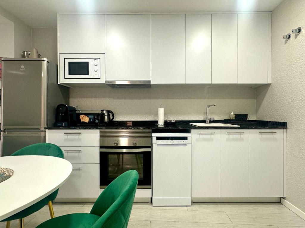 a kitchen with white cabinets and a table with chairs at Reinapart Valencia Beach in Valencia