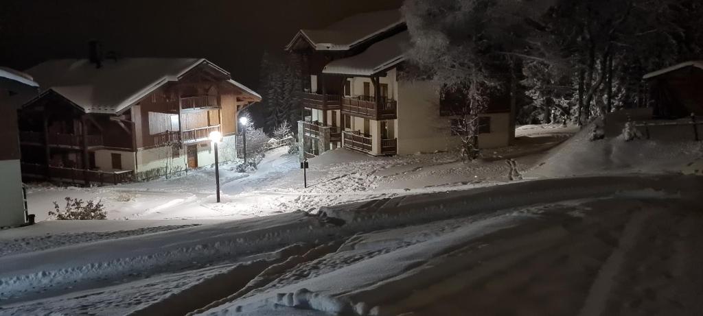 une rue enneigée la nuit avec une maison dans l'établissement Au pied des pistes, dans une résidence de standing, à Cohennoz