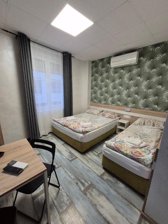 a room with two beds and a desk and a table at Guest House "The House" Топ Център Габрово in Gabrovo