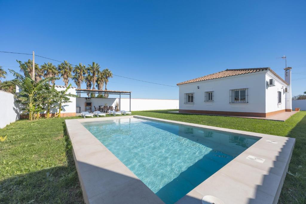 eine Villa mit Swimmingpool und ein Haus in der Unterkunft Chalet La Barrosa in Chiclana de la Frontera
