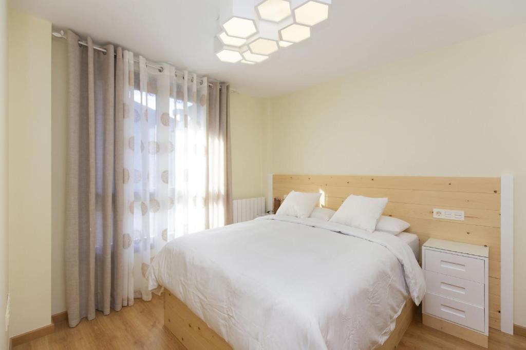 Un dormitorio con una cama blanca y una ventana. en Casa Lite by BeValle, en Escarrilla