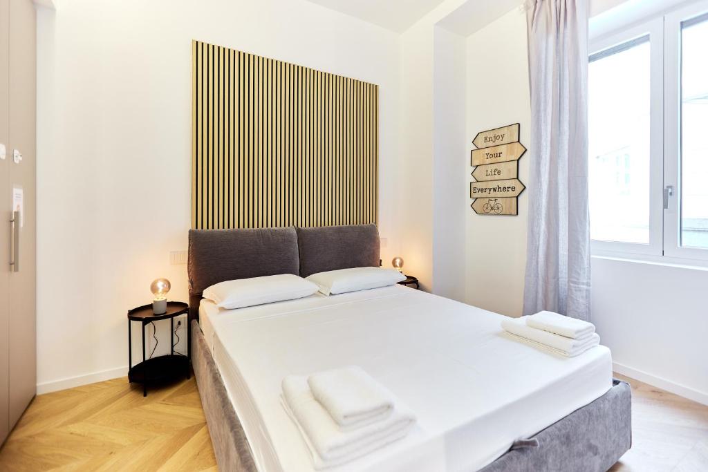 a bedroom with a bed with white sheets and a window at Duomo Imperial Suits - Modern and comfortable in Milan
