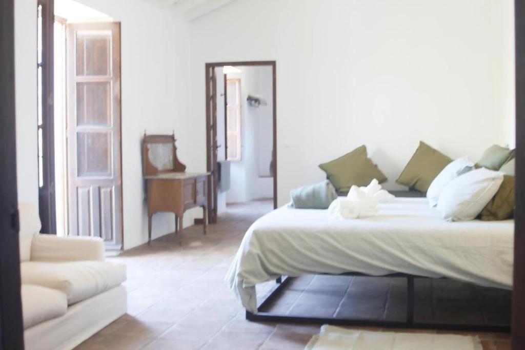 a bedroom with a large white bed and a chair at Lagar De Trevenez Montes De Malaga in Málaga