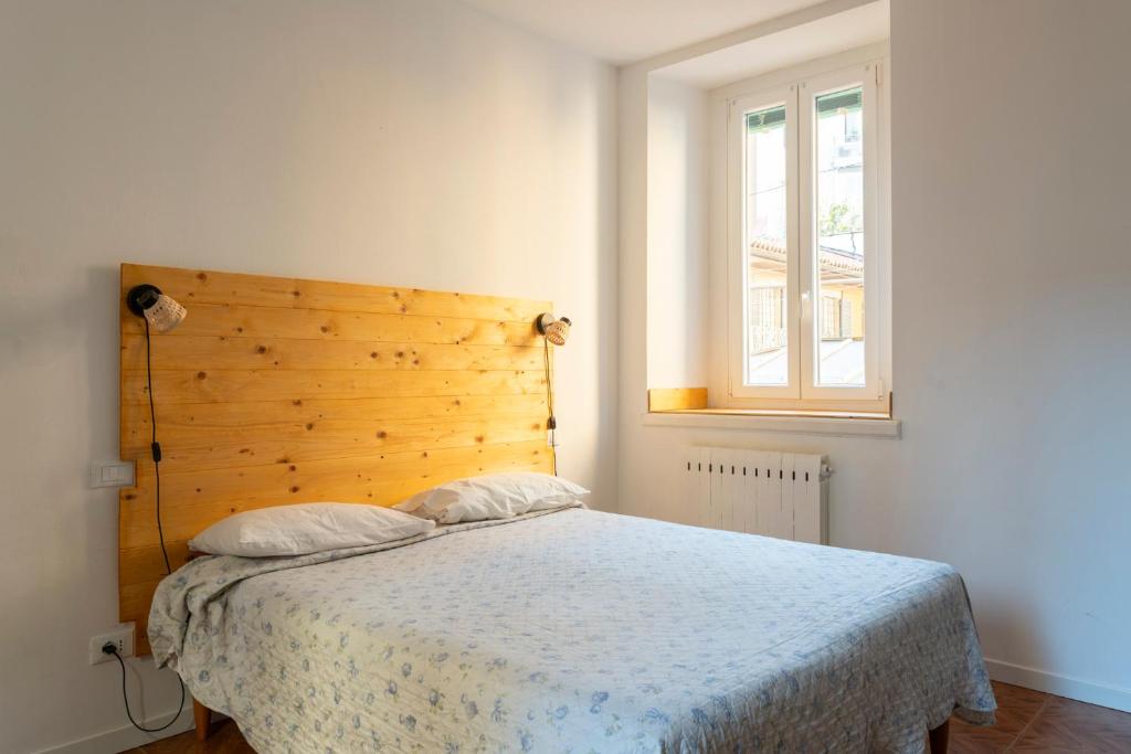 1 dormitorio con 1 cama con cabecero de madera y ventana en Antiche Stalle IV, en Bérgamo