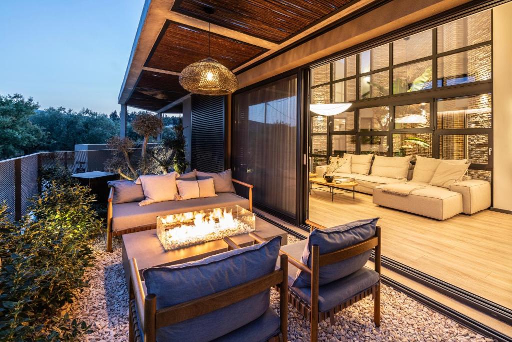 un patio con divano, sedie e camino di Terra Segreda · slow living villa by ikies 3 a Volos