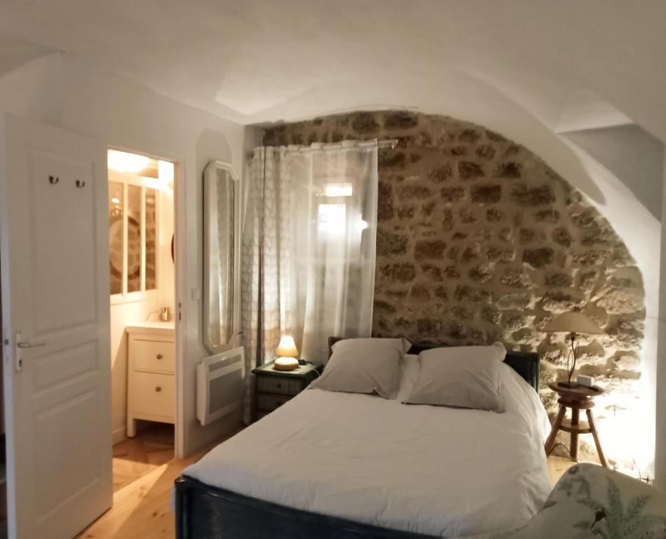 een slaapkamer met een wit bed en een stenen muur bij "La Voûte de Pierre" Gîte indépendant in Saint-Cyr