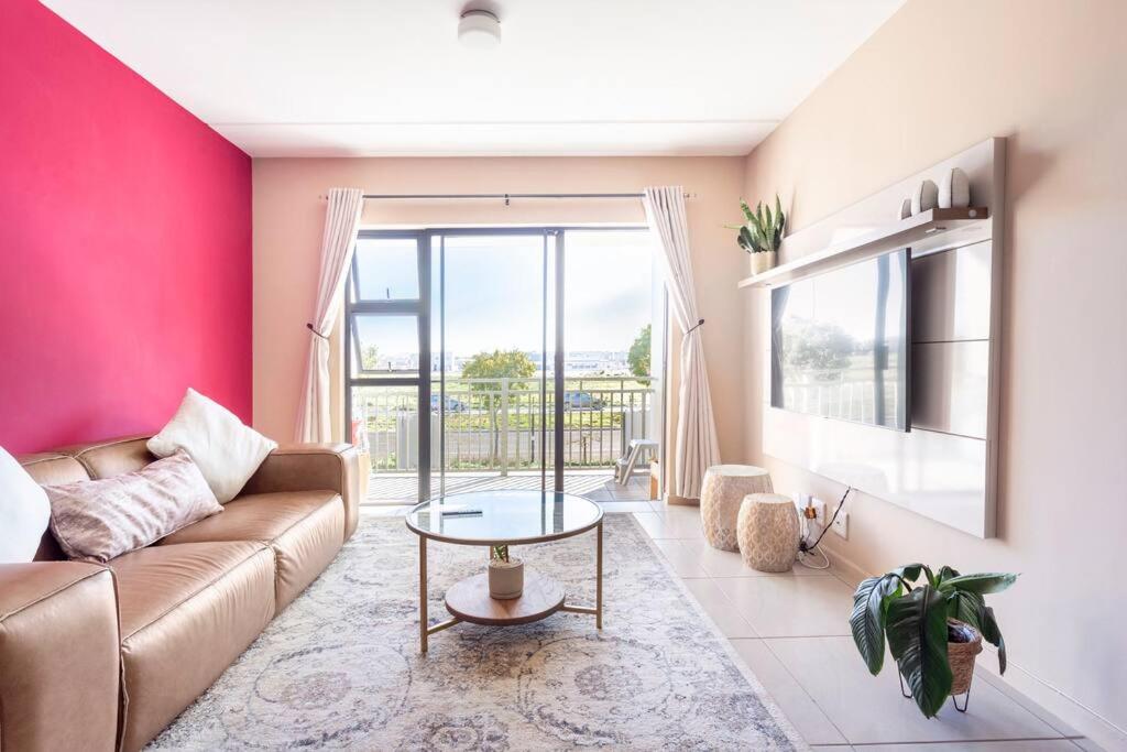 a living room with a couch and a table at The Cozy Retreat, 2-bedroom Apartment in Parklands, Cape Town in Cape Town