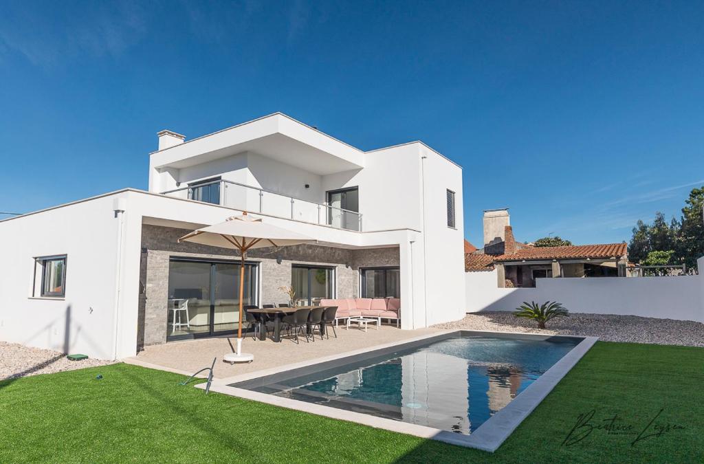 a white house with a swimming pool in the yard at Casa Kiara Silvercoast in Nadadouro