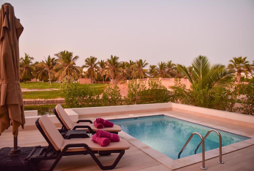 a swimming pool with two lounge chairs next to a swimming pool at Segal Rotana Salalah Villa with private swimming pool in Salalah