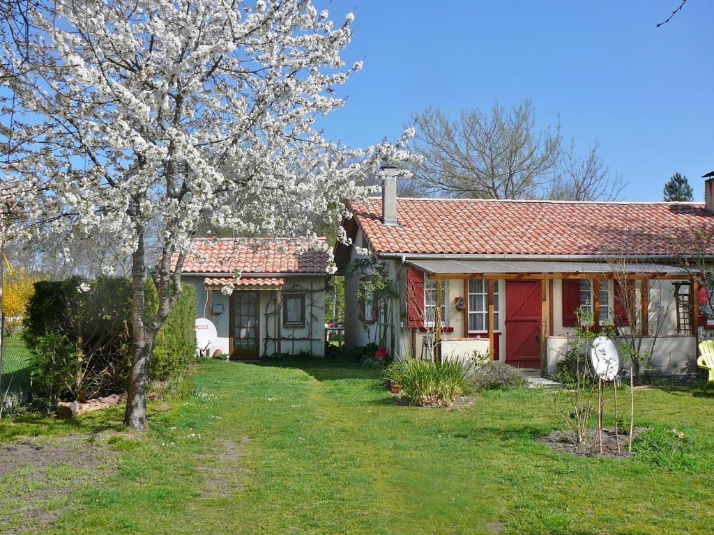 una casa roja y blanca con un árbol en el patio en Guesthouse La Burle, en Parentis-en-Born