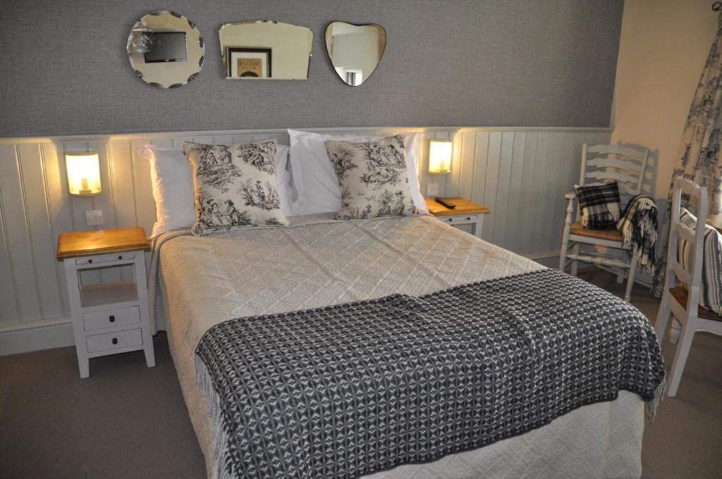 a bedroom with a bed and two tables and two mirrors at Higher Buck Inn in Waddington