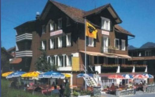 um edifício com uma bandeira e guarda-chuvas à sua frente em Hotel Montana em Seelisberg