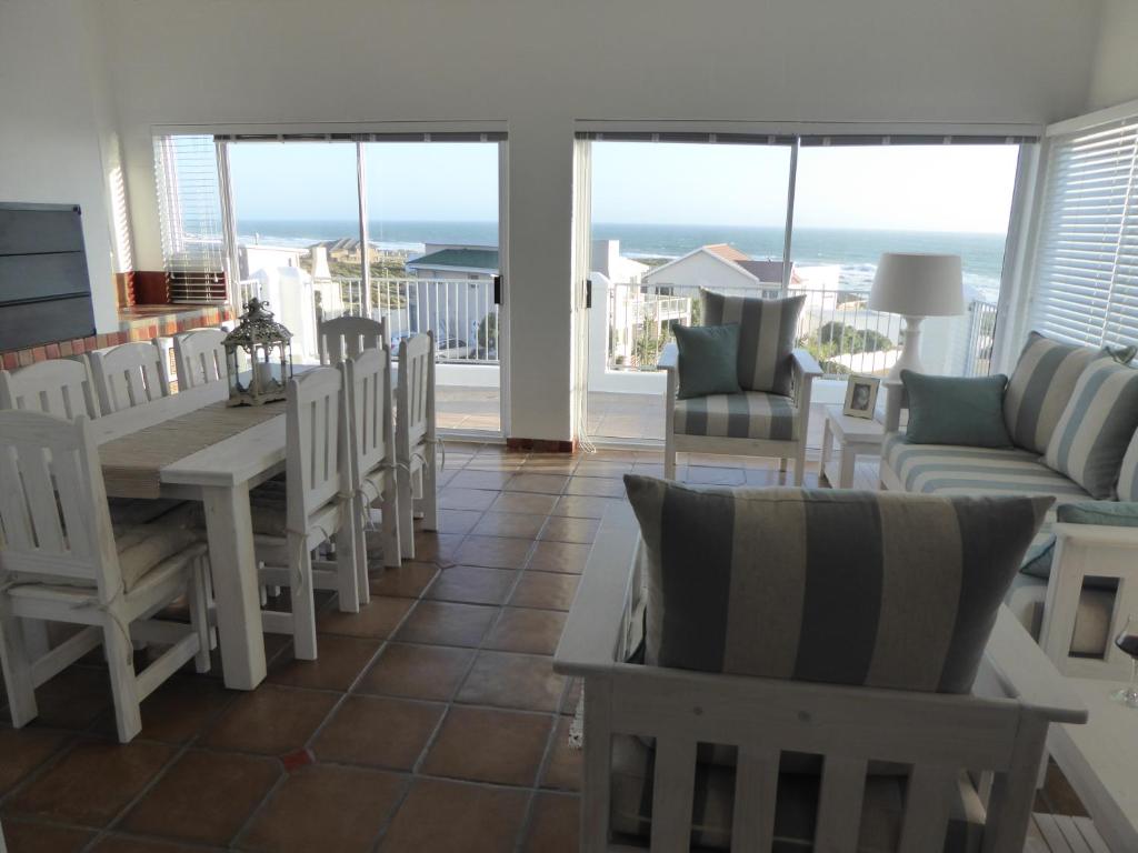 a living room with a table and chairs and the ocean at Seaview Villa in Yzerfontein