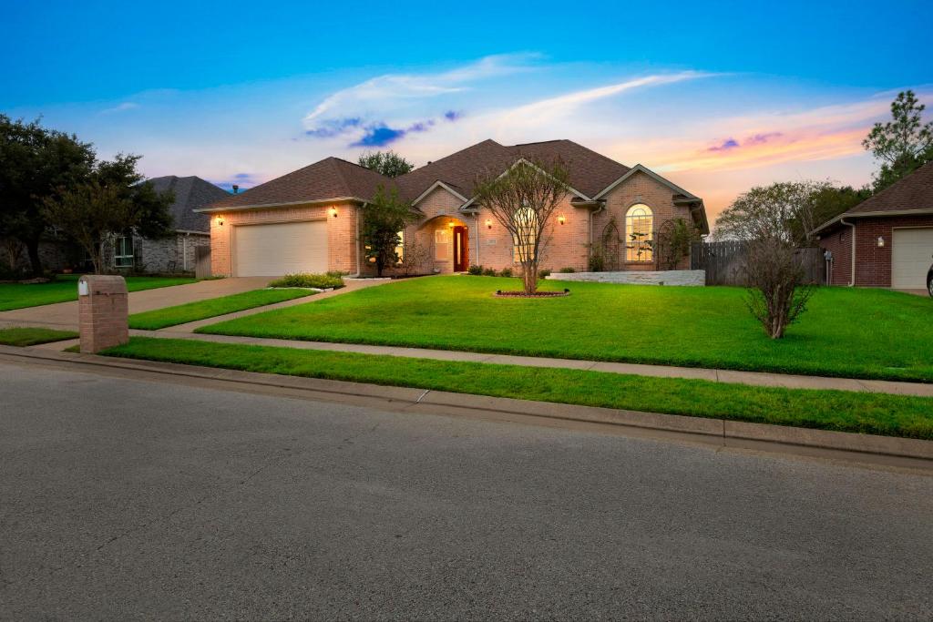 une maison avec une cour verdoyante et une allée. dans l'établissement Luxury Home with Gourmet Kitchen - 3 Miles to A&M, Sleeps 14, à College Station