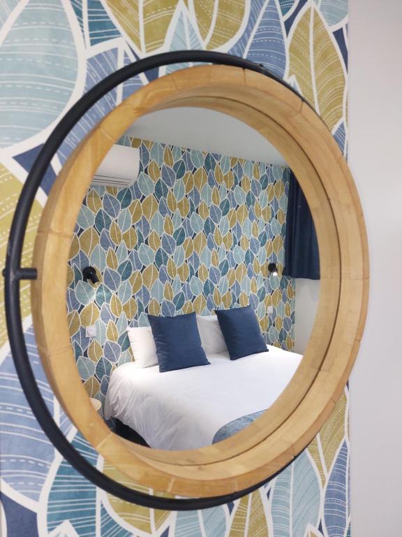 a room with a bed and a round mirror at Logis Loire Hotel - Les Cocottes Restaurant in Les Rosiers