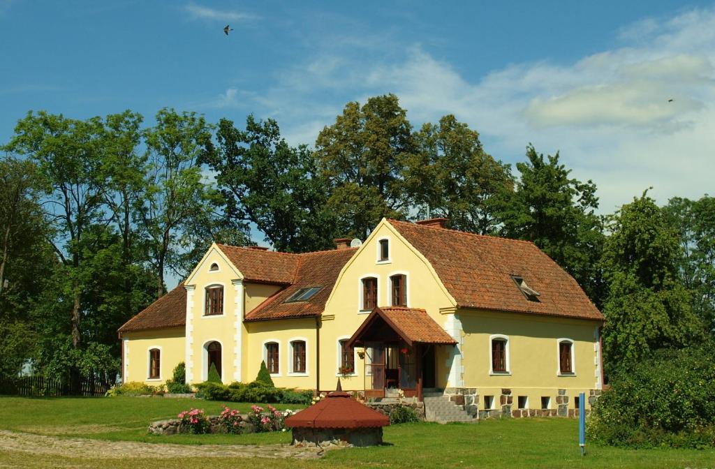 a large yellow house with a brown roof at Dworek Szarki in Szarki