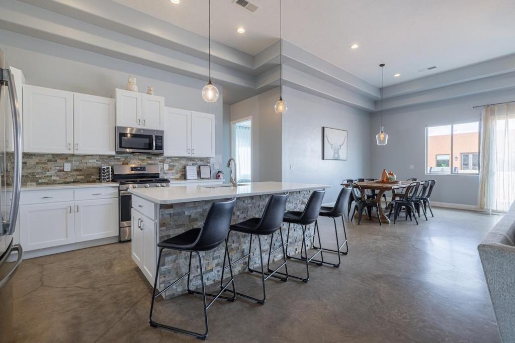 eine Küche mit weißen Schränken und eine Bar mit Hockern in der Unterkunft The Ashley at Sand Hollow Resort in Hurricane