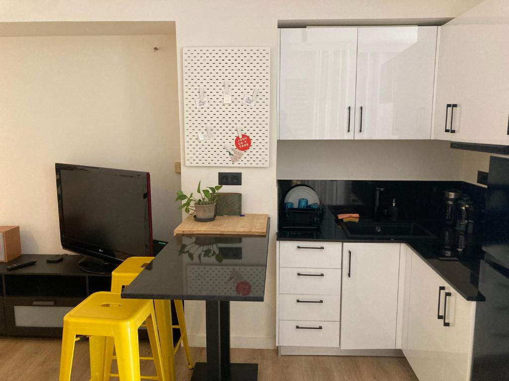 アテネにあるCOSY STUDIO MAISONETTE in ATHENSの白いキャビネット、テーブル、テレビ付きのキッチン