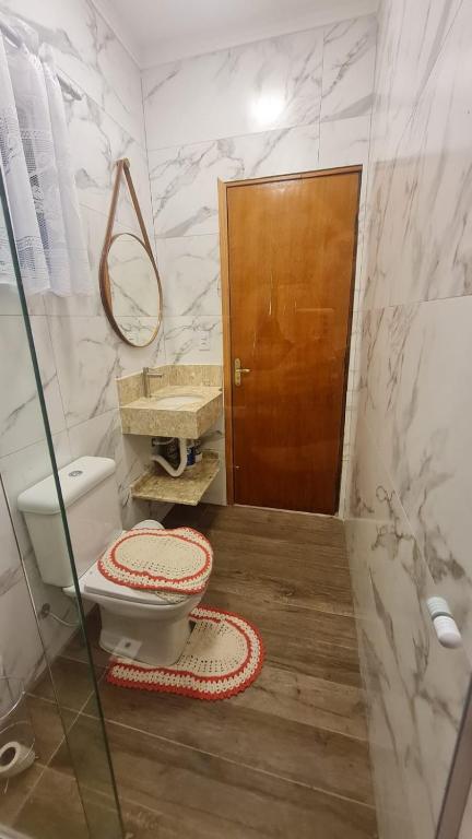a bathroom with a toilet and a wooden door at Kitnets Peruíbe casa 02 in Peruíbe