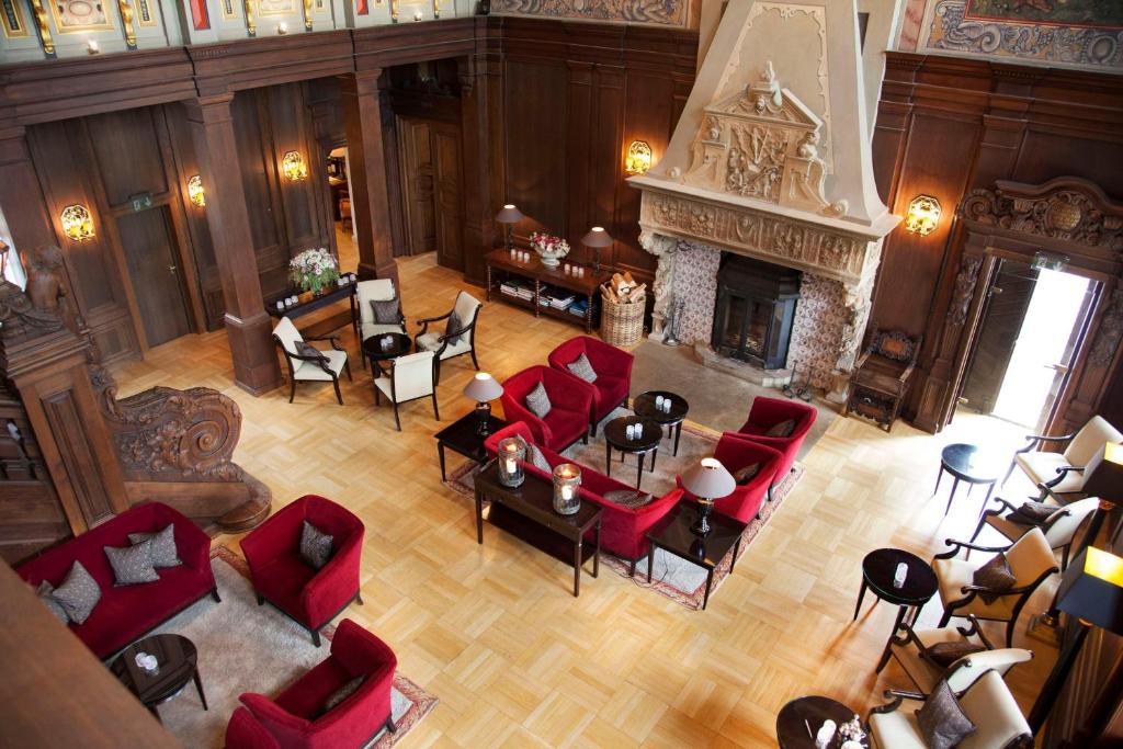 een woonkamer met rode stoelen en een open haard bij Schlosshotel Münchhausen in Aerzen