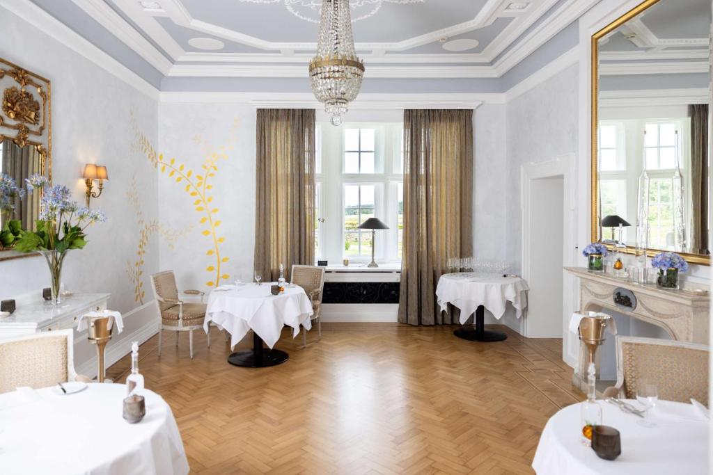 een eetkamer met 2 tafels en een kroonluchter bij Schlosshotel Münchhausen in Aerzen