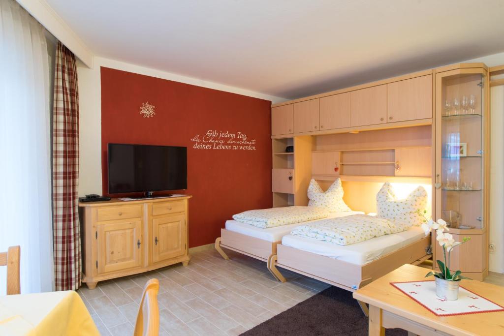 a hotel room with two beds and a television at Nebelhorn Appartementhaus in Oberstdorf