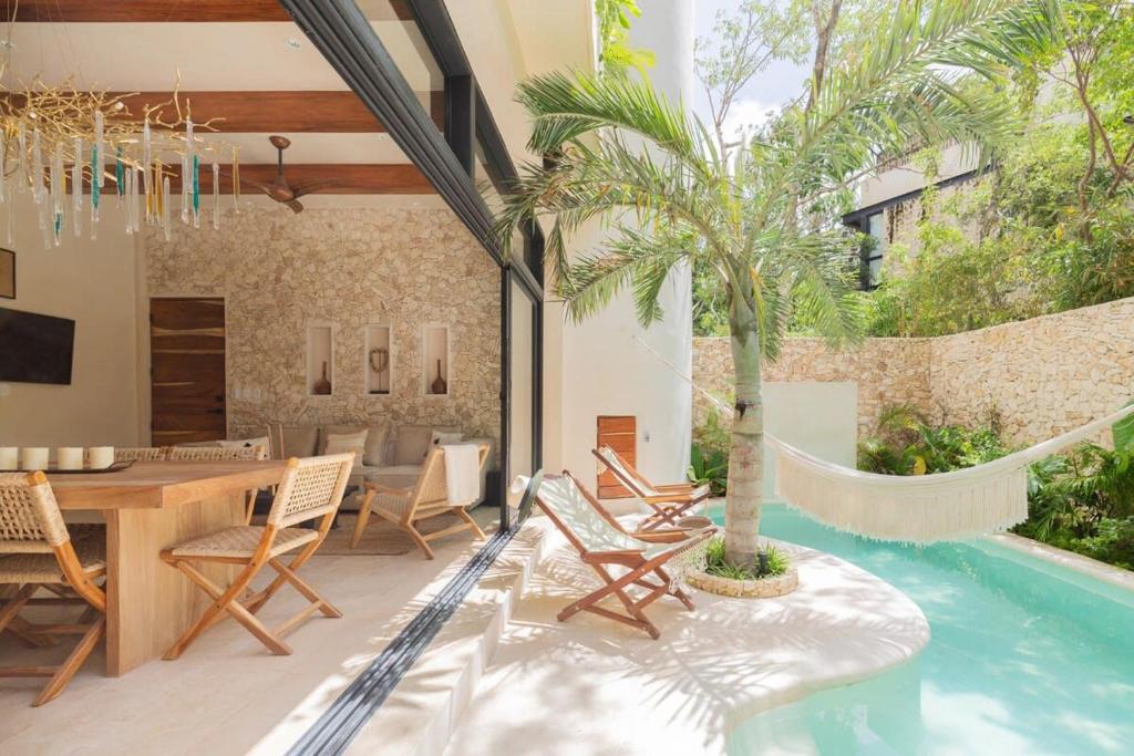 een patio met een tafel en stoelen en een palmboom bij 3BR Villa in Tulum, Pool plus Concierge in Tulum