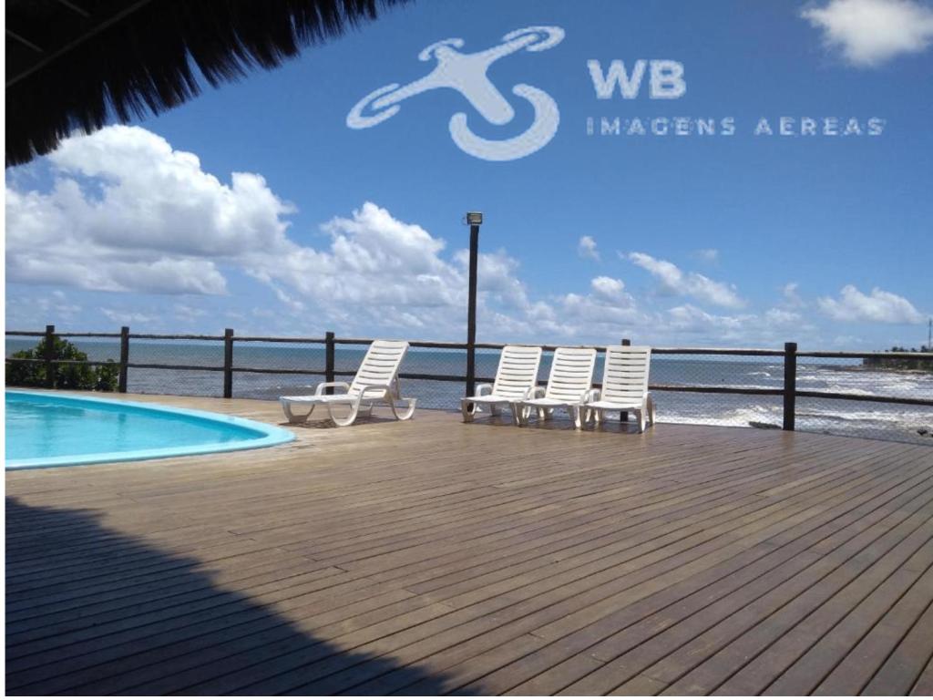 Dos sillas sentadas en una terraza junto a una piscina. en WB Apto condomínio Jubiabá, en Olivença